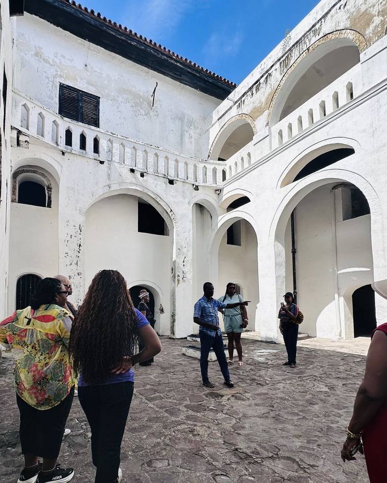 A group touring the courtyard of a castle on Ghana's coast