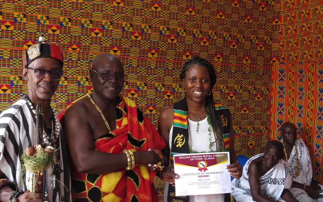 A naming ceremony in a room hung with kente, a certificate being presented